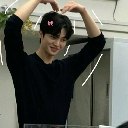 A man smiling while making a heart shape with his hands above his head.