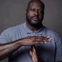 Shaquille O'Neal making a timeout hand gesture with a serious expression.