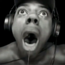 A man with headphones looking upward with his mouth wide open in an expression of extreme shock.
