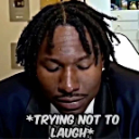 A man looking down with a strained, serious expression while trying to suppress a laugh.