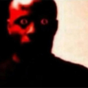 A human face with glowing eyes and a deep red filter staring intensely.