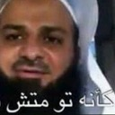 A man with a beard and white head covering looking seriously at the camera with Arabic text overlaid at the bottom.