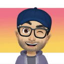 Man with a baseball cap and glasses winking with a friendly smile.