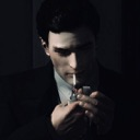 A man in a dark suit lighting a cigarette with a lighter.