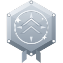 A silver hexagonal badge with upward-pointing chevrons and small circular accents on the corners.