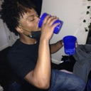 A person wearing a black shirt and face mask drinking from a blue plastic cup.