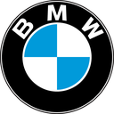 A circular logo with a black border, white letters, and a blue and white checkered center.