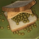 A sandwich made of white bread, a slice of yellow cheese, and a large pile of green peas sits on a green plate.