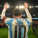 Lionel Messi wearing a number 10 jersey waves to a crowd in a stadium.