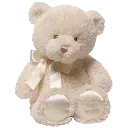 A light-colored plush teddy bear with a ribbon around its neck sitting upright.