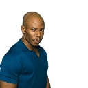 A man with a shaved head wearing a blue polo shirt looks sideways with a suspicious and skeptical expression.