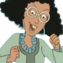 A woman with curly hair and glasses cheering with a wide smile and fists raised in the air.