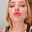 A woman with blonde hair puckering her lips towards the camera in a close-up shot.