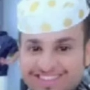 Man wearing a white hat with yellow polka dots smiling broadly at the camera.