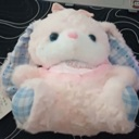A soft pink stuffed bunny plushie with blue gingham ears and feet sitting upright.