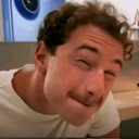 Man with curly hair winking with a smug and playful expression.