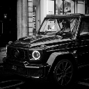 A black luxury SUV driving down a city street in a black and white photograph.
