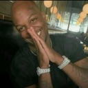 A man with a wide smile pressing his palms together in a gesture of gratitude.