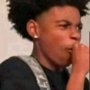 Young man with a fade haircut looking skeptical while covering his mouth with his hand.