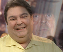 A man smiling in the foreground with a faded, serious version of his face superimposed in the background.