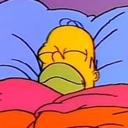 Homer Simpson sleeping peacefully with his head resting on a pillow under a colorful blanket.