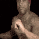 Man wearing a red bandana performs a rhythmic dance move against a black background.